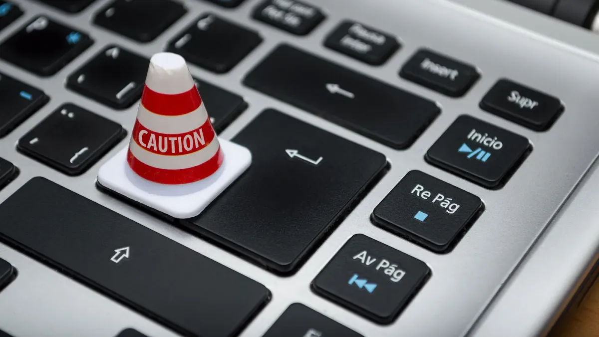 Cone de sinalização em miniatura sobre teclado de computador, símbolo de alerta de segurança de dados