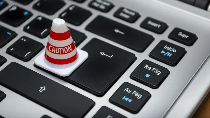 Cone de sinalização em miniatura sobre teclado de computador, símbolo de alerta de segurança de dados